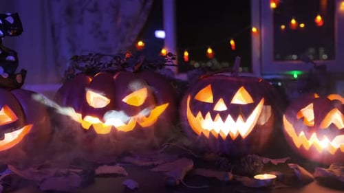 Many carved pumpkins in smoke with different creepy smiles, glowing lanterns from inside