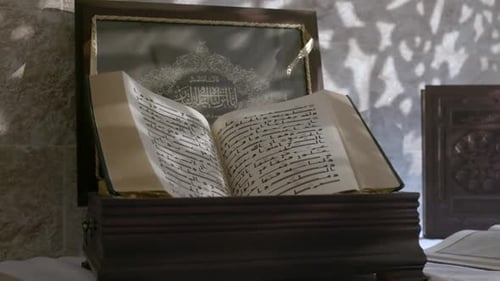 Tracking-Aufnahme eines geöffneten Korans, geschrieben in alter Kufi-Schrift. Der Koran ist der zentrale religiöse Text von Is