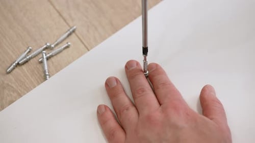 Hand Using Screwdriver to Fasten Furniture