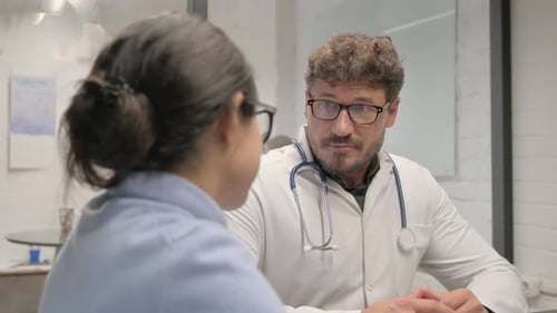 Middle Aged Doctor Talking with Patient in Clinic