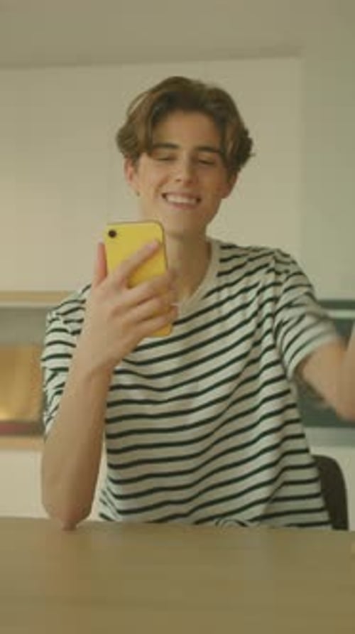 Young Adult Video Chatting on Phone at Table