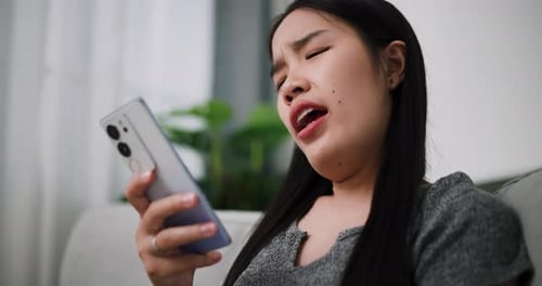 Woman Looking at Cell Phone, Expressing Frustration
