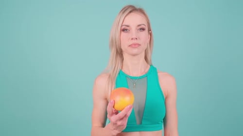 Smiling Woman Holding Orange Against Blue Background