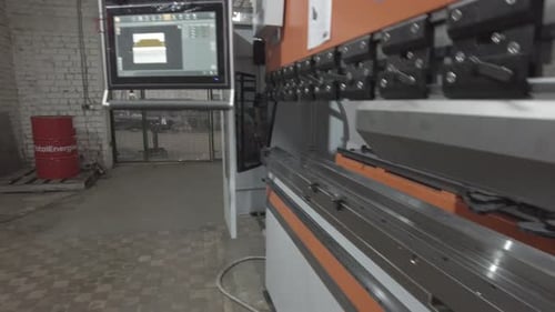 Man Operates Metal Bending Machine in Factory