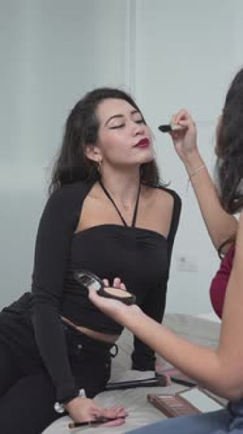 Young Woman Applying Makeup on Friend Indoors