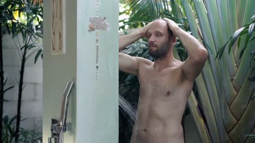 Man washing hair outdoors in a tropical shower