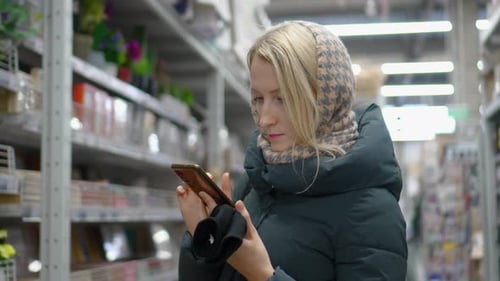 Young Caucasian woman in supermarket store to look at mobile phone