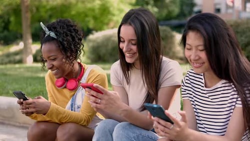 Young Multiracial Woman Friends Having Fun Using Mobile Phones in the Street