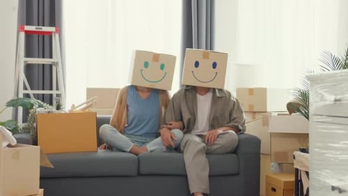 couple used carton box made smiling face funny dance front of camera in living room at new house.
