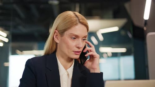 Business Woman Speaking on Smartphone at Office Workplace Noticing in Notebook