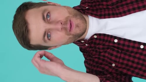 Caucasian Young Man with a Tired Face in the Studio on a Blue Background Vertical Video