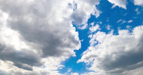 Two big clouds meet in the horizon forming one. Sky being covered with cloudscape. View from below.