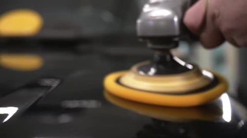Car polish with a yellow grinding machine close up in 50fps, slow motion ready