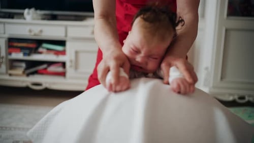 Crying Infant Held by Female on Exercise Ball
