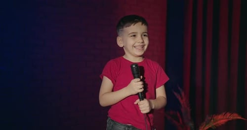 Happy Boy Sings into Microphone on Stage