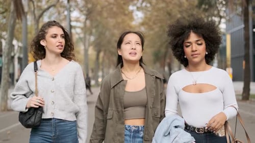 Three Multiethnic Friends Talking While Walking Along the Street