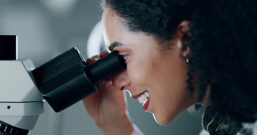 Woman Looks Through Microscope in Lab Close Up