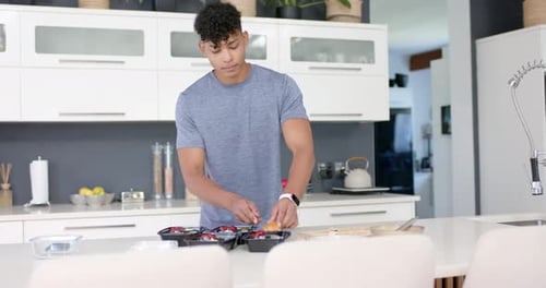 Homme afro-américain cueillant une tranche avec un couteau, remplissant des plateaux noirs en pressant des plateaux noirs dans la cuisine pour le déjeuner