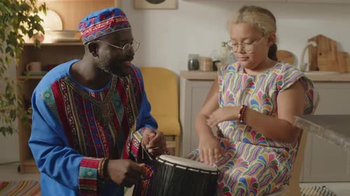 Man and Child Playing a Drum Together Indoors