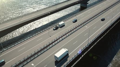 Traveling car and trailer drive across a scenic bridge over a river.