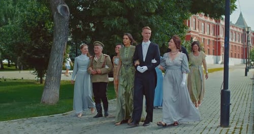 Elegant Ladies in Historical Dresses with Lace Walk Arm in Arm with Gentlemen Nobles on the Streets