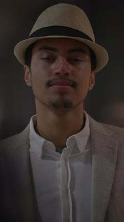 A Young Man Sporting a Stylish Hat and Sharp Suit Under the Night Sky in the City