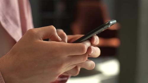 Closeup Side View Shot Hands of Unrecognizable Young Man Typing at Smartphone