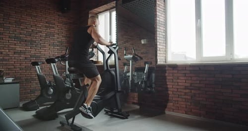 A Man Does Sports in the Gym on an Exercise Bike