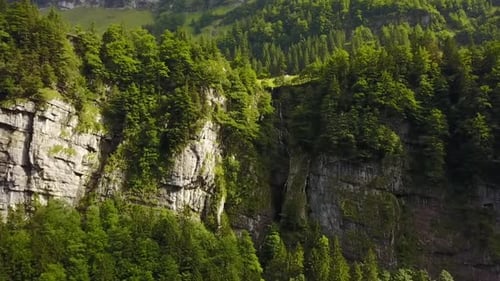 forward flight towards a cliff with a small waterfall in the middle