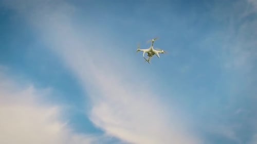 Drone Flying in a partly cloudy blue sky