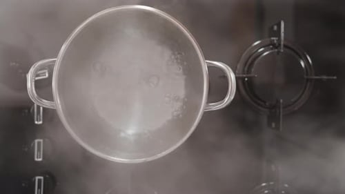 On the black gas stove, water is boiling in a silver pot. I lift the lid, and steam bursts out.