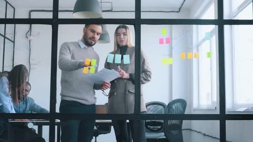 Bunch of stickers on the glass. Professional workers are in the modern office together.