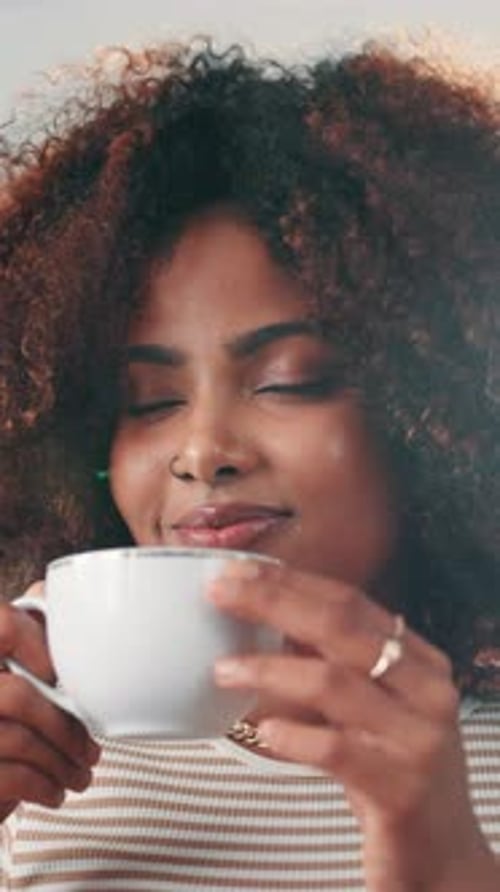 Curly-haired Woman Enjoying the Aroma of a Warm Beverage