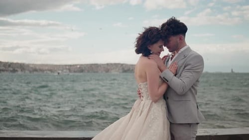 Cute newlywed couple embracing at the beach on their wedding day. Action. Bride and groom in love