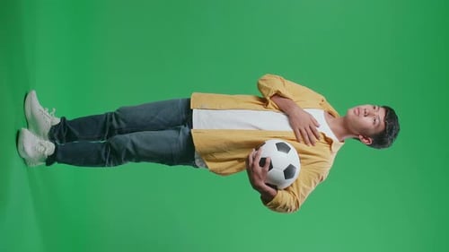 Young Adult Holds Soccer Ball on Green Screen