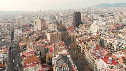 Aerial flying forward over Barcelona rooftops and buildings on a clear warm day.4K