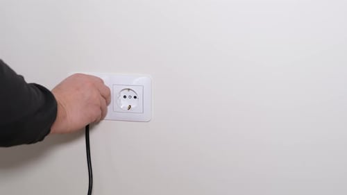 A Man's Hand Disconnects the Plug From a Modern Electrical Outlet 120 Volts