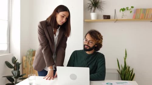 Two Colleagues Collaborating on Laptop in Modern Office
