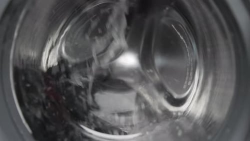 Waschen in der Waschmaschine: Die Trommel mit Schaum und Wasser dreht sich um die Hausarbeit