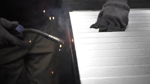 Metal welder works with a steel welder in a factory with protective equipment. Manufacture of metal