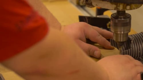 Man's hands drilling wood with milling machine