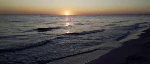 Sunrise Reflections on Slow Motion Sea Ripples