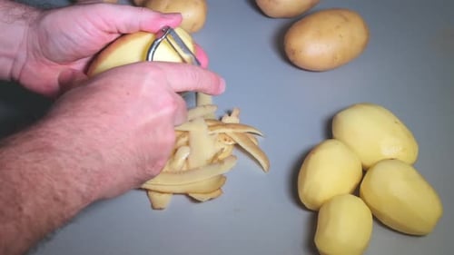 Man Peeling Potatoes for Meal Preparation at Home