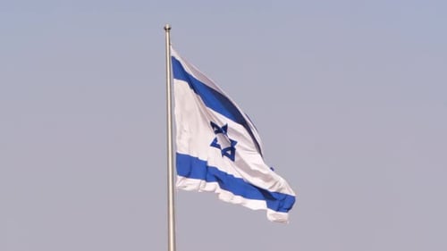 Israeli Flag Waving in the Wind Against Blue Sky