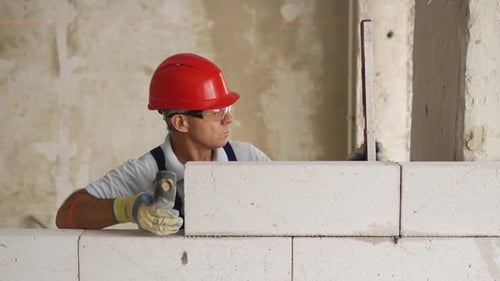 Bricklayer Using Rubber Mallet Hammer to Tap and Level Concrete Blocks Wall Contractor Uses Precise