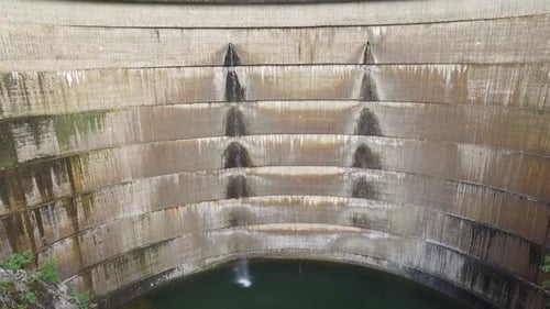 Drohnenaufnahme von Wasser, das auf dem Damm fließt. Blick auf den Flusskanal. Aufnahme nach oben kippen.