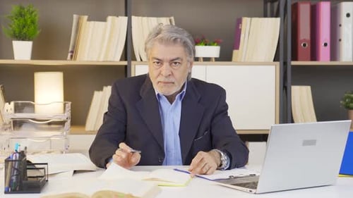 Man Working At Desk With Laptop and Books