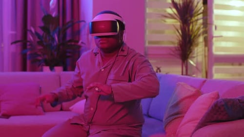 Close Up Mixed Race Young Man Wearing Virtual Reality Headset Sitting on Sofa Move Hands at Home