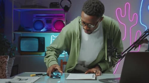 African American Man Vlogging at Home Recording Studio with Neon Light
