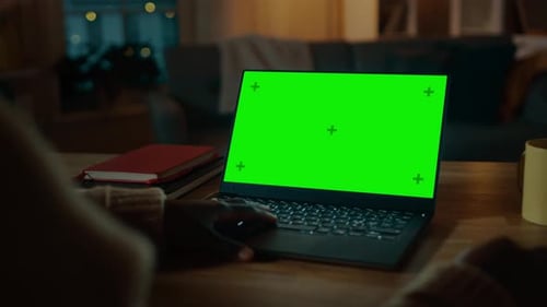 Beautiful Black Woman Sitting at Her Desk Works on a Laptop with Green Chroma Key Screen. Late at N